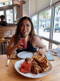 a woman sitting at a table with a plate of food and drink in front of her