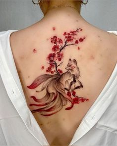 the back of a woman's neck with a fox and flowers on it