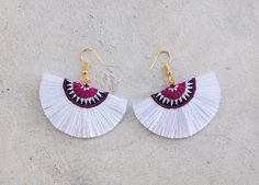 two pairs of white fan shaped earrings with red beads