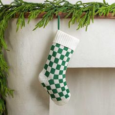 a green and white christmas stocking hanging from a mantel