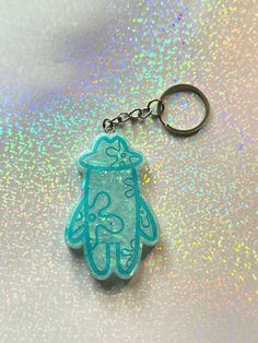 a blue keychain with a hand drawn hamsa on it