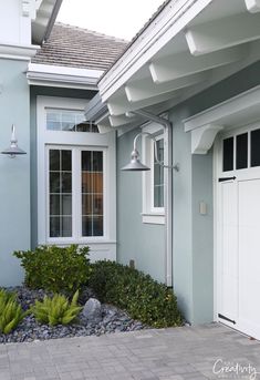 a blue house with two white garage doors on the front and side of the house