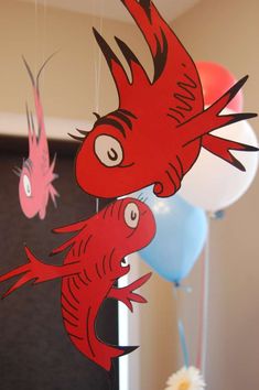 two red fish hanging from the ceiling next to balloons