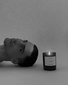 a man laying on the ground next to a candle