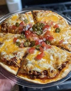 a person holding up a pizza with cheese and toppings