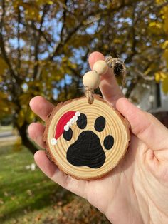 a hand holding a wooden ornament with a dog's paw on it