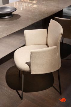 a chair sitting on top of a wooden floor next to a table with chairs around it