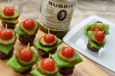 small appetizers with tomatoes and cucumber on skewers next to a bottle of beer