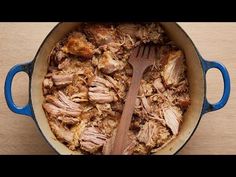 a blue pot filled with meat on top of a wooden table