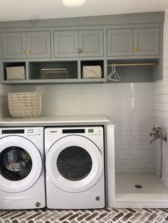 a washer and dryer in a small room with gray cupboards on the wall