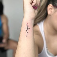 a woman with a cross and flower tattoo on her left arm is looking at the camera