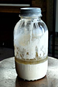 a glass jar filled with liquid sitting on top of a wooden table