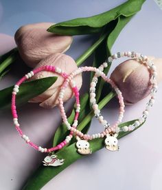 three bracelets with flowers and charms on them