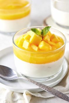 a dessert with mango and yogurt in a glass bowl on a white plate