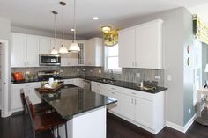 a large kitchen with white cabinets and black counter tops, along with an island in the middle