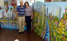 a man and woman standing next to a large painting on the side of a wall