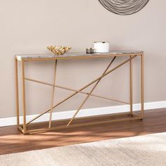 a console table with marble top and gold metal frame, in front of a beige wall