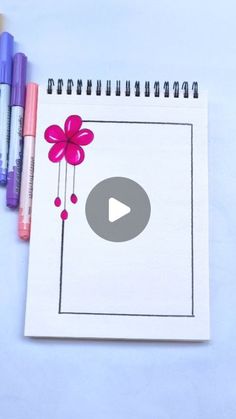 a spiral notebook with a flower drawn on it and crayons next to it