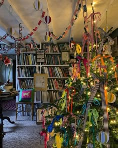 a decorated christmas tree in the corner of a room with bookshelves and lights