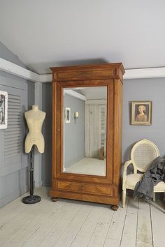 a large mirror sitting on top of a wooden floor next to a chair and lamp