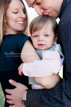 a man and woman holding a baby in their arms