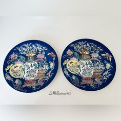 two blue plates with designs on them sitting next to each other in front of a white wall