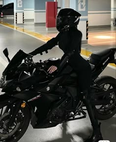 a woman in black is sitting on a motorcycle