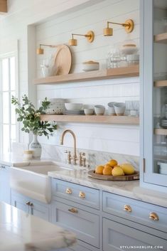 a kitchen with marble counter tops and gold faucets on shelving above the sink