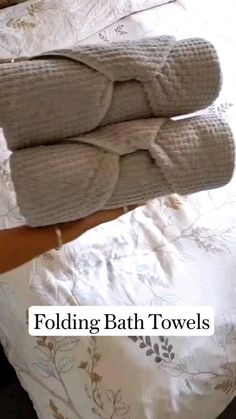 two folded towels sitting on top of a bed next to each other with the words folding bath towels