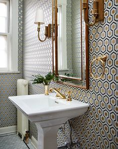 a white sink sitting under a bathroom mirror next to a wall mounted faucet