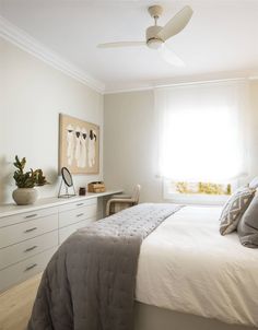 a bedroom with a bed, dressers and ceiling fan in front of a window