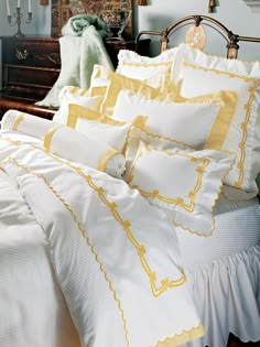 a bed with white and yellow comforters on top of it in a bedroom next to a dresser