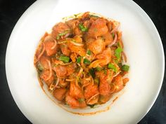 a white plate topped with meat and vegetables on top of a black countertop next to a fork