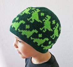 a young boy wearing a green and black knitted beanie with crosses on it