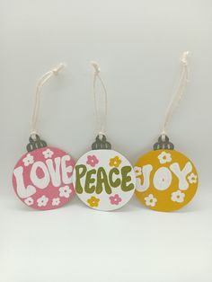 three ornaments with the words love, peace and joy on them