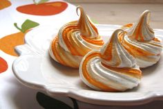 three orange and white meringue desserts sitting on a plate next to each other