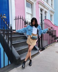 a woman standing in front of some stairs with her arms out and one hand on the railing