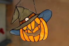 a stained glass hanging lantern with a witch hat on it's head and mouth