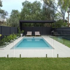 an empty swimming pool in the middle of a backyard with grass and trees around it