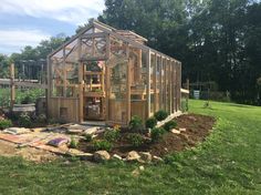 a small wooden greenhouse sitting on top of a lush green field