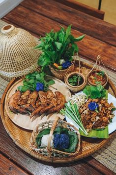 an assortment of food items on a wooden table with wicker baskets and bamboo hats