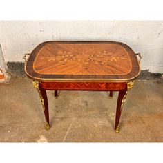 a small table with an intricately decorated top and gold trimmings on the legs