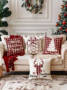 christmas pillows are sitting on a couch in front of a christmas tree and other decorations