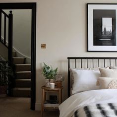 a bed with white sheets and pillows in a bedroom next to a stair case on the wall