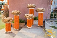 three tall vases with flowers in them sitting on the side of a building next to a potted plant