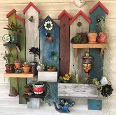 colorful birdhouses are on the wall with pots and plants in them as well as other decorations