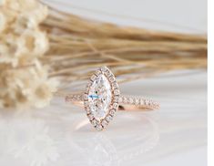 a close up of a ring on a table with dried flowers in the back ground