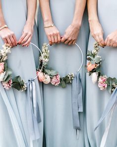 four bridesmaids in blue dresses hold their flower hoop wreaths with flowers on them