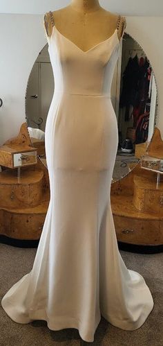 a white wedding dress on display in front of a mirror with a mannequin