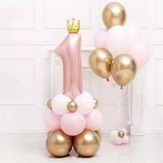 the balloon column is decorated with gold and pink balloons, which are shaped like a number one